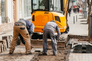 İşçi traktör arkaplanına fayans yerleştiriyor