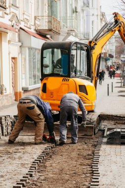 İşçi yığını traktör arkaplanında taş kaldırıyor