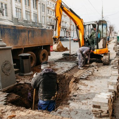İnşaatçılar şehirdeki boruların altından kanal yapıyorlar.