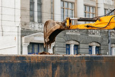 Tratkor kovası toprağı kazdı ve başka bir arabaya yükledi.