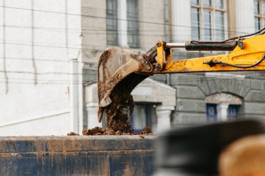 Traktör bir arabaya kil yükler.