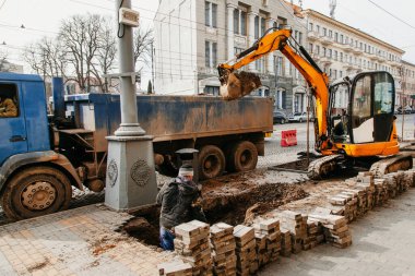 Sarı traktörü ve inşaatçısı olan bir şehirde onarım işlemi