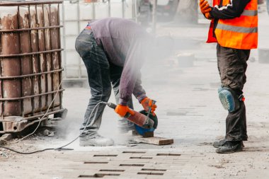 Çalışan adam kaldırım taşlarını keser.