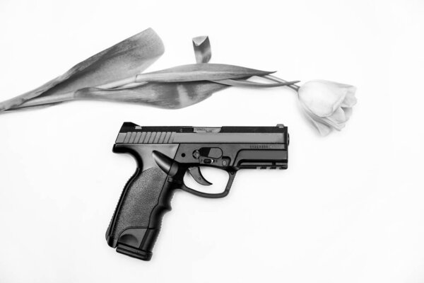 The gun lies near the tulip. Top view on a white background