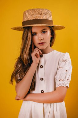 Sarı arka planda şapkası olan genç ve zeki bir kızın portresi..