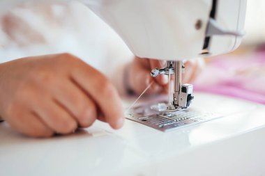 Terzi dikiş makinesindeki iğneye iplik takıyor.