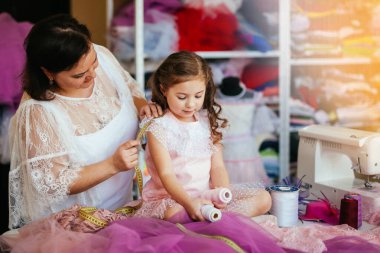 Kadın terzi bir kızın omzunun ölçüsünü alır.