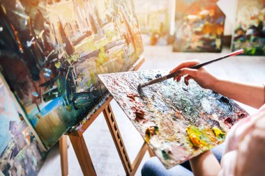 Kız ressam tuvale yağlı boya resim yapıyor. Paleti fırçala