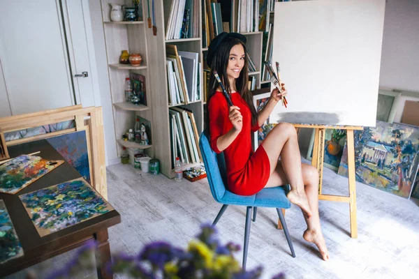 artist girl with bare legs sits on a chair in the studio
