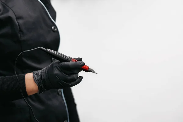 Master beautician holding a tattoo machine