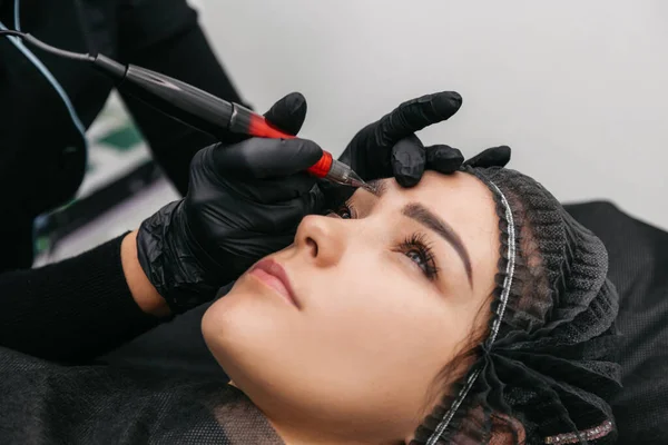 Master beautician applies permanent on eyebrows.