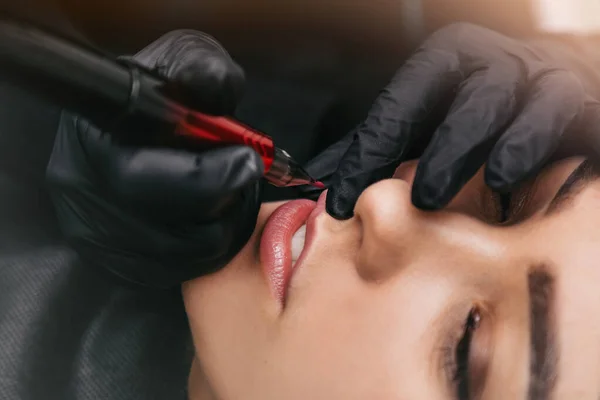 beautician in the hospital makes lip tattoo, pink pigment