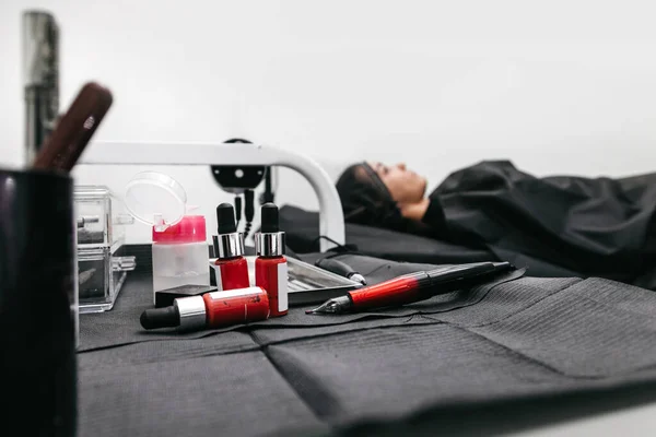 Masanın Üzerinde Kırmızı Dövme Makinesi Var Hasta Arka Planda — Stok fotoğraf