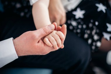 Baba bebeğinin elini tutuyor.