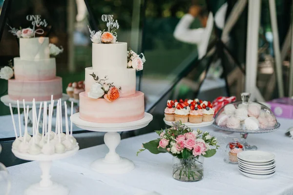 Delicate and pink cake on a table with sweets. Goodies for a birthday