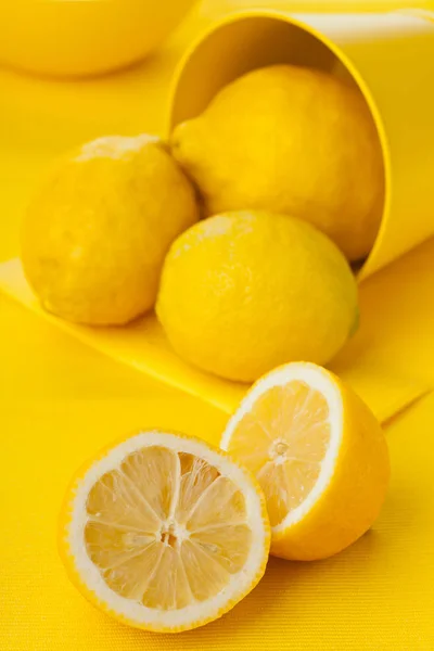 Limones orgánicos enteros y cortados sobre mesa amarilla —  Fotos de Stock