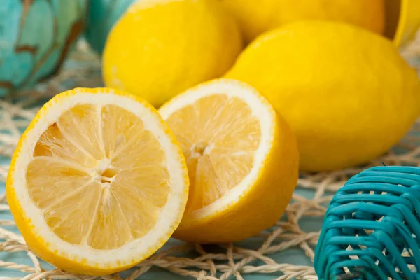 Limones orgánicos enteros y cortados sobre mesa turquesa —  Fotos de Stock