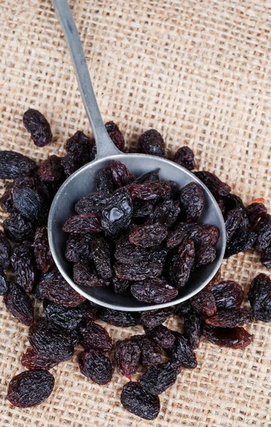 Organic raisins in rustic metal spoon — Stock Photo, Image