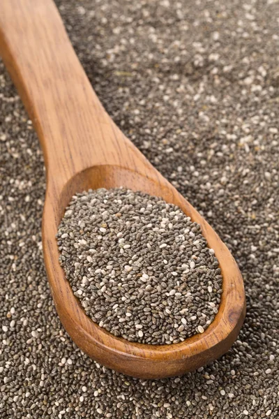 Raw unprocessed black chia seeds on wooden spoon on chia seeds — Stock Photo, Image
