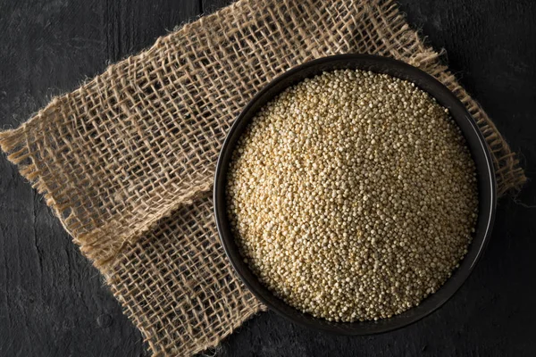 Rå, hela, obearbetade quinoa frön i skål på träskiva — Stockfoto