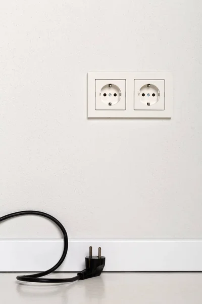 Black power cord cable unplugged with european wall outlet on wh