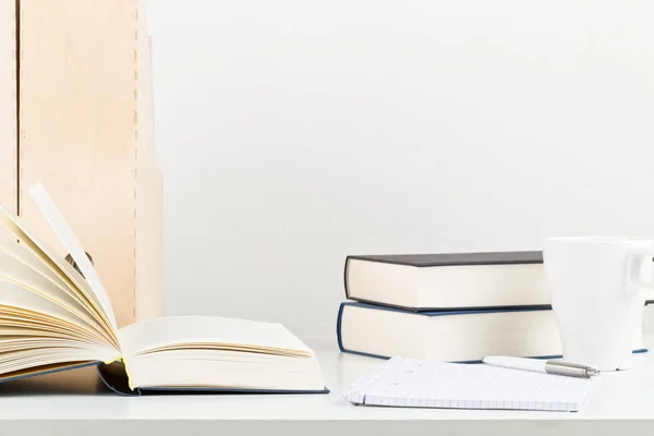 Escritório branco com livros, bloco de notas e xícara — Fotografia de Stock