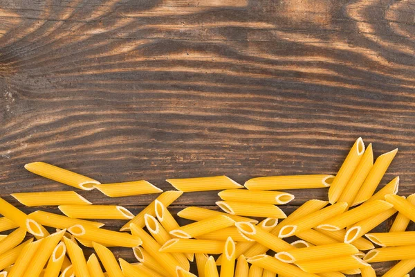 Çiğ, çiğ, Kuru penne makarna erişte üzerinde rustik kahverengi wo sınır