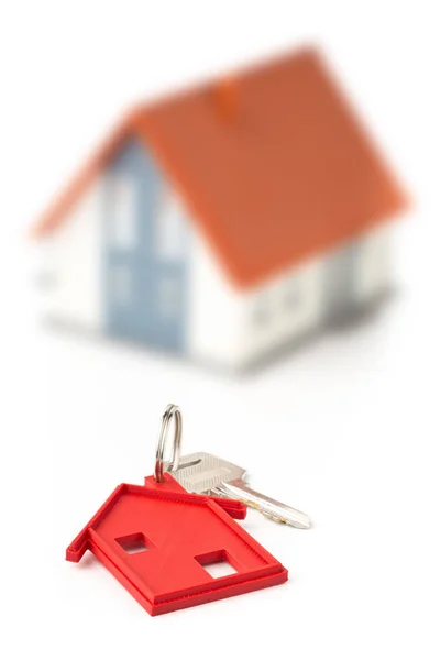 Llave de la puerta de la casa con llavero rojo colgante y casa modelo —  Fotos de Stock