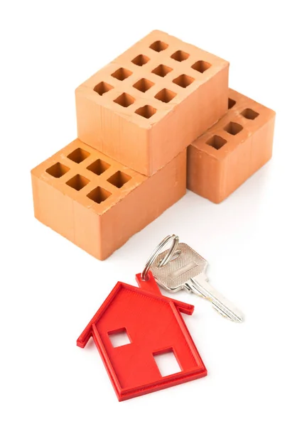 House door key with red house key chain pendant and bricks — Stock Photo, Image