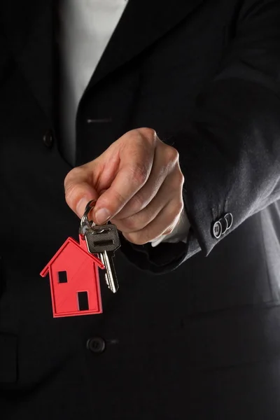 Homem segurando chave da porta da casa com pingente chaveiro casa vermelha — Fotografia de Stock