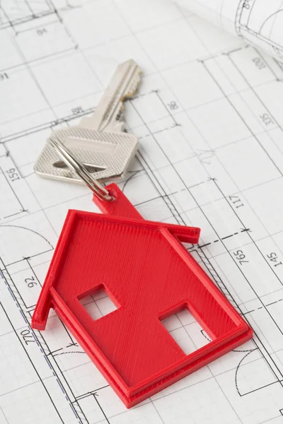 House door key with red house key chain pendant on building plan — Stock Photo, Image