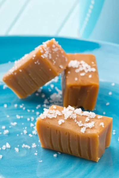 Hand made caramel toffee pieces on plate with sea salt — Stock Photo, Image