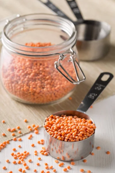 Raw red, dried  lentils in measurement scoop and glass — Stock Photo, Image