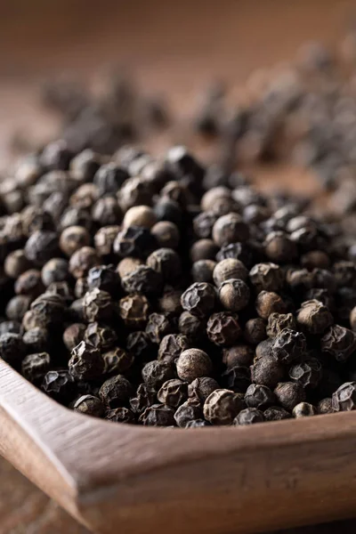 Raw, natural, unprocessed black pepper peppercorns on wooden pla — Stock Photo, Image