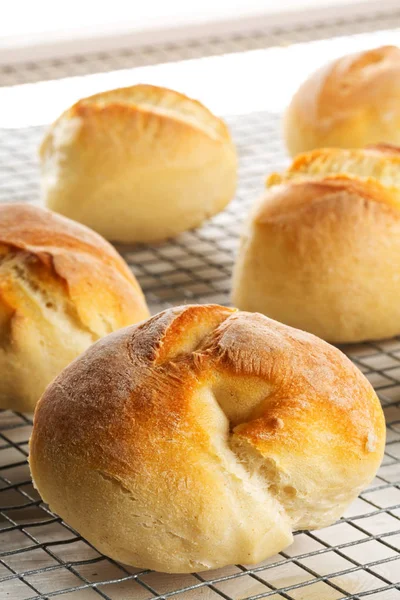 Bündel von ganzen, frisch gebackenen Weizenbrötchen auf Kühlgestell auf weiß — Stockfoto