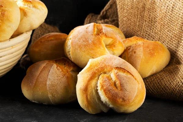 Bunch of whole, fresh baked wheat buns on dark wooden table — Stock Photo, Image