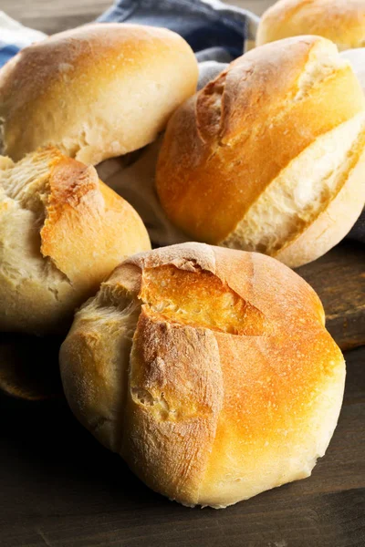 Bündel voller, frisch gebackener Weizenbrötchen auf dunklem Holztisch — Stockfoto