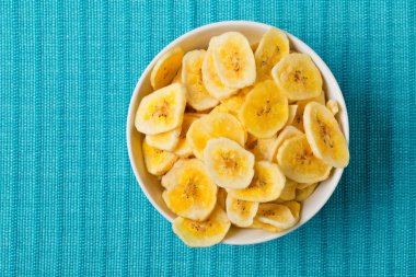 Kurutulmuş muz yığını snack üzerinde mavi turkuaz beyaz kase cips