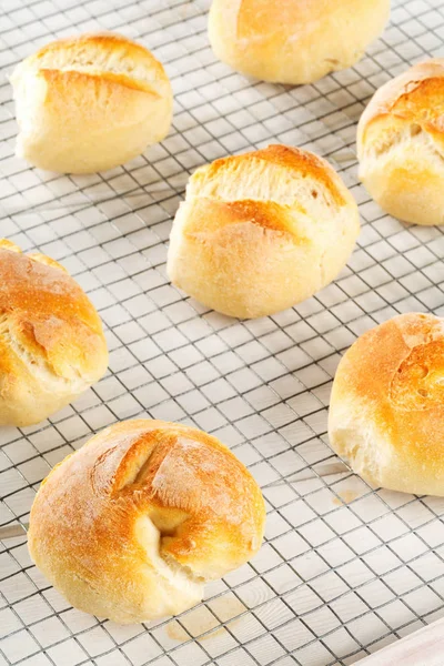 Bündel von ganzen, frisch gebackenen Weizenbrötchen auf Kühlgestell auf weiß — Stockfoto