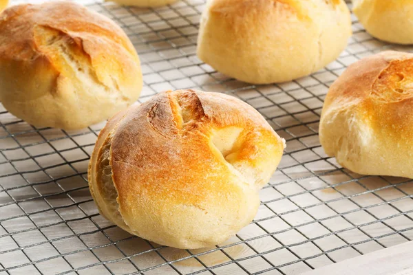 Bündel von ganzen, frisch gebackenen Weizenbrötchen auf Kühlgestell auf weiß — Stockfoto