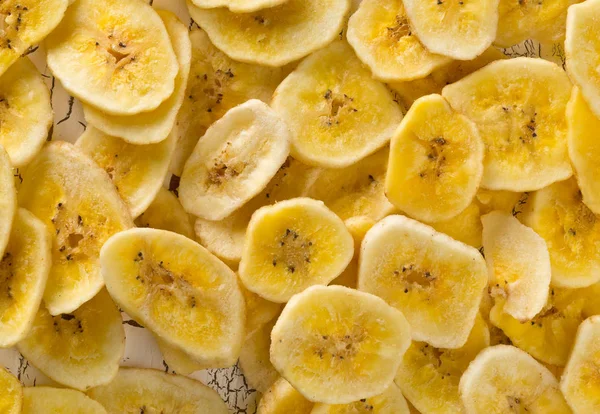 Halom szárított banán chips, snack a fehér rusztikus asztal — Stock Fotó