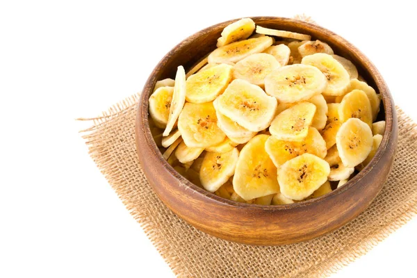 Heap of dried banana chips snack in wooden bowl over white — Stock Photo, Image