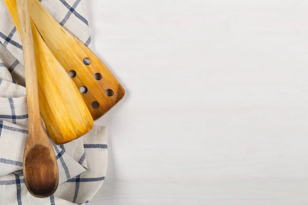 Colheres de madeira com toalha de cozinha azul e branca em madeira branca — Fotografia de Stock