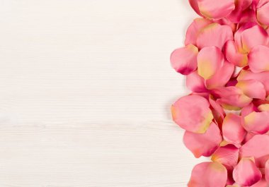 Pembe kumaş gül yaprakları beyaz ahşap masa arkaplanının sınırında 
