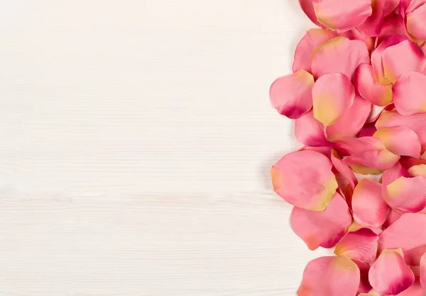 Pink fabric rose petals border over white wood table background — ストック写真