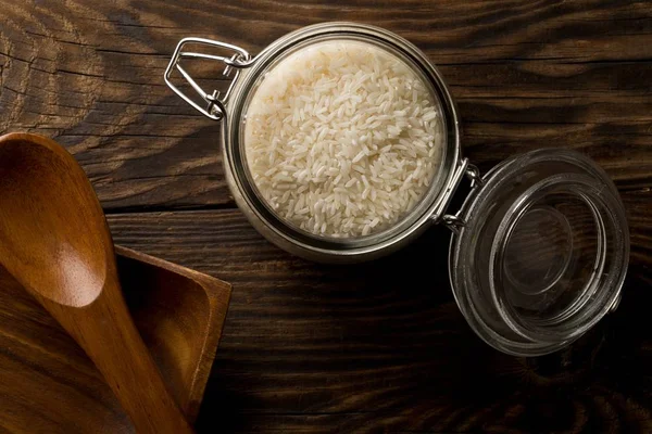 White uncooked, raw long grain rice in glass storage jar — Stock Photo, Image