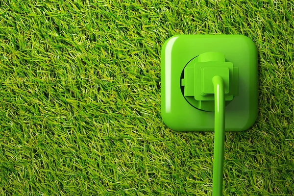 Green power cord in wall socket on grass background with copy space — Stock Photo, Image