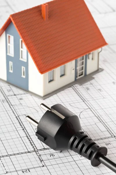 Power cord on building construction blueprint plan with model house — Stock Photo, Image