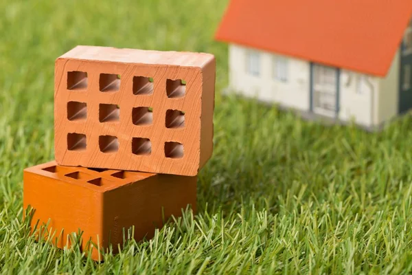 Miniature bricks with house model on green grass lawn background — Stock Photo, Image