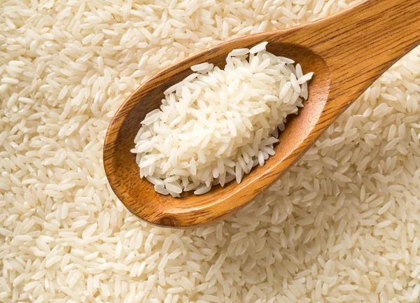 White uncooked, raw long grain rice full frame with wooden spoon — Stock Photo, Image